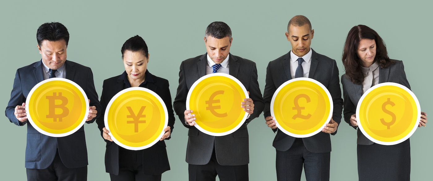 Social Trading Gruppe, 5 Personen halten je ein rundes Schild, die die Währungssymbole von Bitcoin, Yen, Euro, Pfund und US-Dollar zeigen